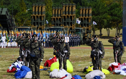 28일 경기도 평택 해군 제2함대 사령부에서 열린 국군의 날 행사에 국군의 최신 무기들이 도열해 있는 가운데 강하시범에 나선 특전사 장병들이 착지 후 경례하고 있다. 국군의날 행사가 해군기지에서 열리는 것은 창군 이후 처음이다. 이번 행사에선 우리 군의 북한 타격용 무기들을 대거 공개했다.  안주영 기자 jya@seoul.co.kr