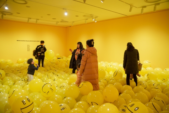 이모그램이 인쇄된 노란 공 1000개로 채워진 전시 공간에서 관람객들이 즐거워하고 있다. 롯데갤러리 제공