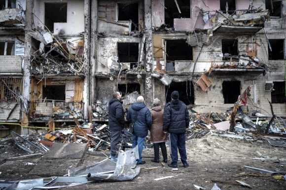 우크라이나 시민들이 러시아의 공격으로 무너진 건물을 바라보고 있다. 2022.02.25 AP 연합뉴스