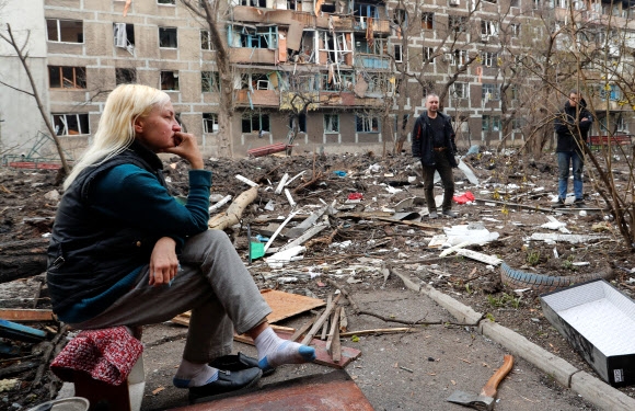 ‘파괴된 삶터’에 망연자실한 우크라 여성 우크라이나 남부 항구도시 마리우폴에서 18일(현지시간) 한 여성이 러시아군의 무차별 폭격으로 파괴된 주거단지 앞마당에 망연자실한 표정으로 앉아 있다. 6주 넘게 러시아군의 포위 공격을 받은 마리우폴은 도시 기반시설의 90% 이상이 파괴돼 이곳 주민들은 식량, 식수, 전기 공급이 끊긴 채 하루하루를 연명하고 있다. 2022.4.19 마리우폴 로이터 연합뉴스