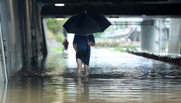 새벽부터 폭우가 쏟아진 30일 오전 침수된 서울 은평구 불광천에서 시민이 무릎까지 찬 물살을 헤치고 발걸음을 재촉하고 있다. 2022.06.30. 뉴시스