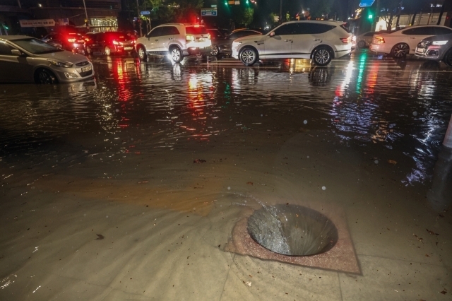 9일 새벽 폭우로 다수의 차량이 침수된 서울 강남구 대치사거리의 배수구가 뚜껑이 없어진 채 소용돌이치고 있다. 연합뉴스 