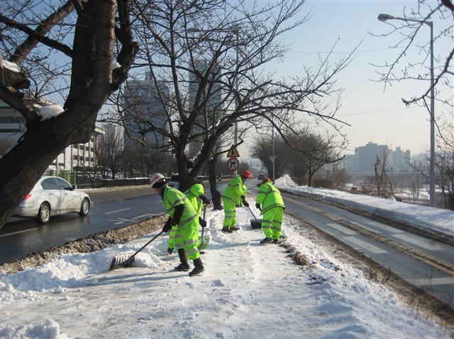 용역 환경미화원들이 지난 11일 서울 여의도의 한 도로에서 ‘1·4 폭설’ 때 쌓여 얼어붙은 눈을 제설도구로 제거하고 있다. 