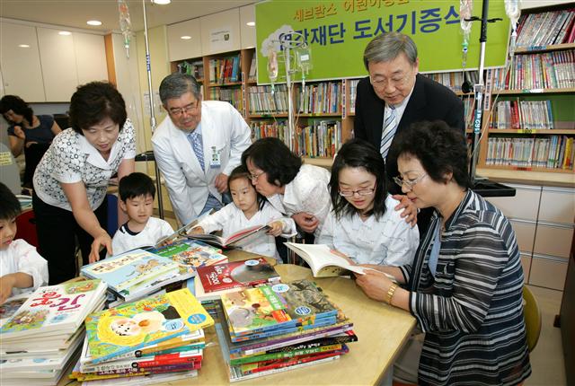 박용현(뒷줄 오른쪽)회장이 세브란스병원의 어린이병원학교를 방문해 연강재단이 기증한 책들을 보고 있다. 두산 제공