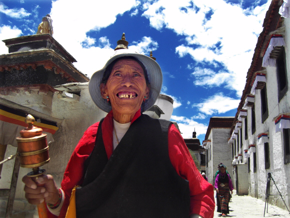 지난 1일 티베트 제2도시 시가체의 최대 사원인 따시룬포 사원을 찾은 티베트 순례객이 불교 경전이 적혀 있는 마니차를 돌리며 환하게 웃고 있다. 시가체 박홍환특파원 stinger@seoul.co.kr