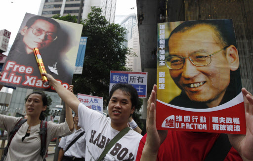 중국 민주화를 요구하는 시위대가 10일 홍콩에서 ‘류샤오보를 석방하라’는 문구와 사진이 담긴 피켓을 들고 홍콩 주재 중국연락사무소로 행진하고 있다.  홍콩 AP 특약