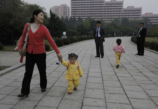 지난 11일 평양 시내의 한 공원에서 나들이복 차림을 한 여성이 아이의 손을 잡고 오붓이 산책을 즐기고 있다.  평양 AP 특약
