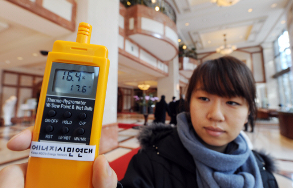24일 오후 서울 태평로 한 업무용 빌딩 1층 로비에서 에너지시민연대 소속 직원이 실내온도 17.6도로 측정된 디지털 온도계를 들어 보이고 있다. 도준석기자 pado@seoul.co.kr