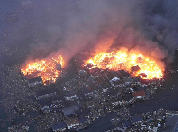 물에 잠긴 미야기현 나토리시 일대 주택가가 화염에 휩싸여 있다.  도쿄신문 제공