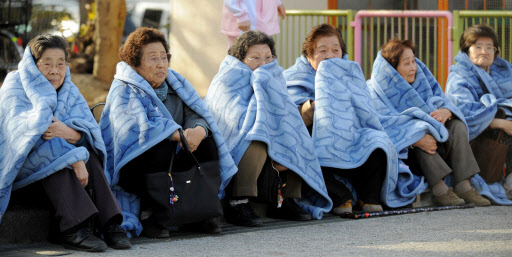 도쿄에서 지진으로 보금자리를 잃은 할머니들이 담요를 덮어쓴 채 길가에 앉아 있다.  연합뉴스