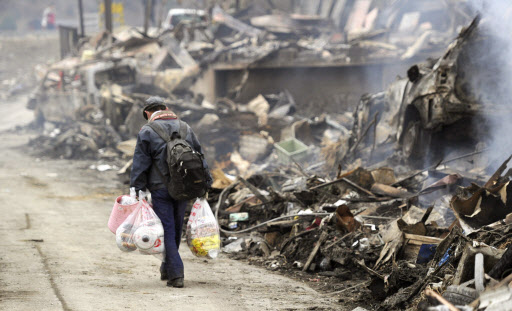 15일 오전 미야기현 게센누마에서 한 이재민이 폐허 앞을 지나가고 있다. 연합뉴스