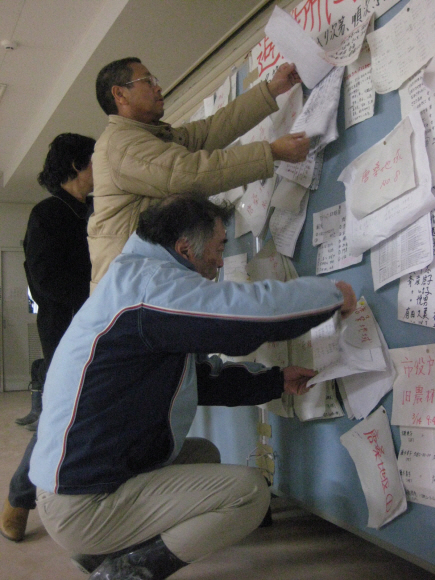 미야기 현 게센누마 시의 한 대피소에서 16일 생존자들이 실종된 가족들을 찾는 전단을 게시판에 붙이고 있다.