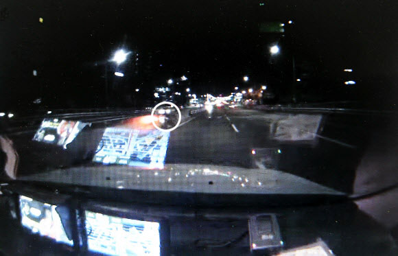 강대성씨의 교통사고 직전 한 영업용 택시의 블랙박스(CCTV)에 찍힌 화면. 택시 앞 1차로에 오토바이(원 안)가 가로등을 받고 비스듬히 서 있고, 도로에는 피해자가 누워 있다. 서울 영등포경찰서 제공