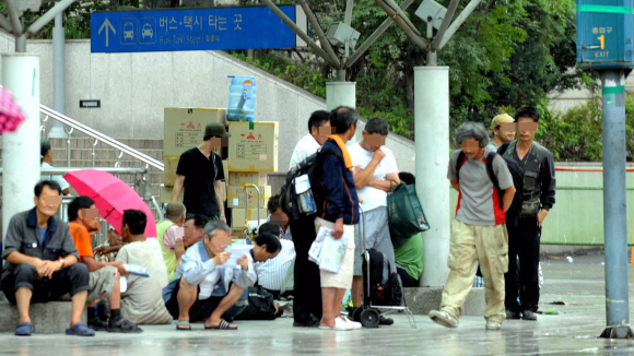 코레일의 서울역 노숙인 강제 퇴거 조치를 하루 앞둔 31일 오후 서울역 역사로 올라가는 계단 앞에서 노숙인들이 쏟아지는 비를 피해 모여 있다. 이호정기자 hojeong@seoul.co.kr