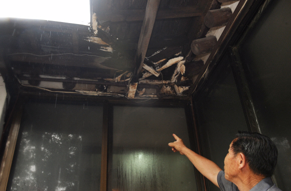 종로구 안국동에 있는 윤보선 전 대통령 사저에서 관리 직원이 파손된 안사랑채 뒤쪽 기와지붕 부분을 가리키고 있다.