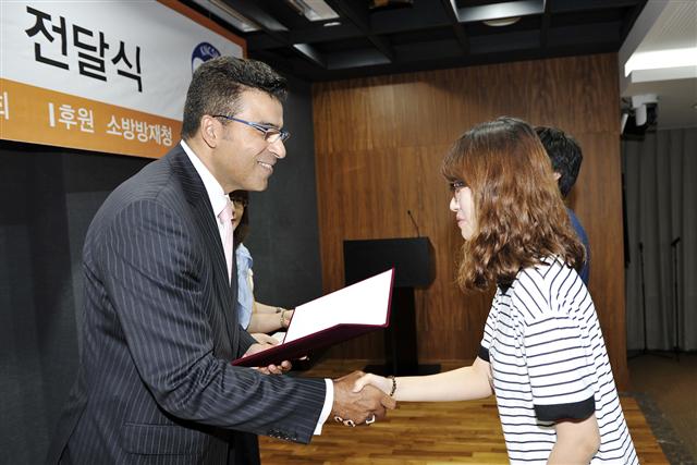 아흐메드 에이 수베이(왼쪽) S-오일 CEO가 25일 서울 마포구 공덕동 본사 대강당에서 소방관 자녀에게 장학증서를 전달하며 악수를 하고 있다. S-오일 제공