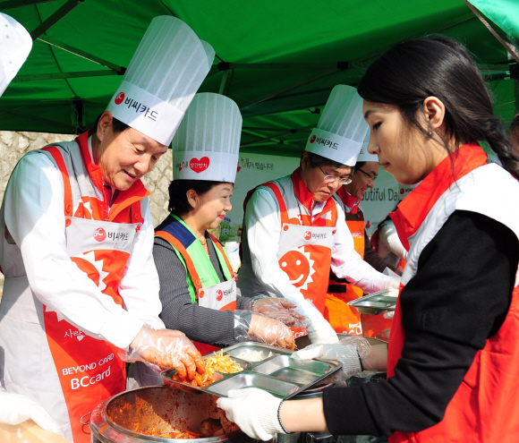 지난 8일 비씨카드 이종호(왼쪽) 사장과 임직원들이 서울 중구 만리동 손기정공원에서 지역노인과 장애인에게 배식할 식사를 담고 있다.