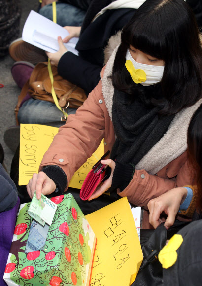 제1000차 일본군 ‘위안부’문제 해결을 위한 정기 수요시위가 14일 오후 서울 중학동 주한일본대사관 앞에서 열렸다. 집회에 참가한 한 학생이 전쟁과여성인권박물관 건립 모금함에 성금을 하고 있다.  연합뉴스