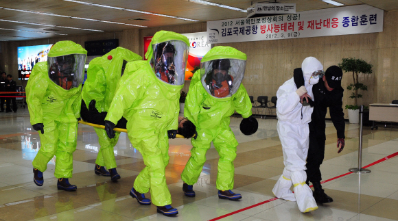 9일 김포공항 국제선청사에서 열린 서울 핵안보정상회의 대비 방사능 테러 대응훈련에서 방호복을 입은 테러 대응팀이 방사성 폭발물에 부상한 경찰과 폭발물처리반을 현장에 마련된 비상진료소로 옮기고 있다.  