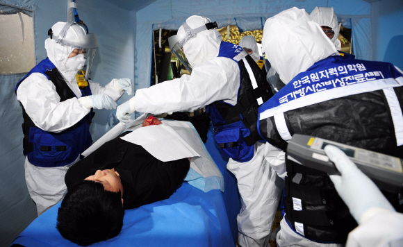 9일 김포공항 국제선청사에서 열린 서울 핵안보정상회의 대비 방사능 테러 대응훈련에서 대응팀이 방사성 폭발물에 부상당한 경찰과 폭발물처리반을 현장에 마련된 비상진료소에서 방사능 오염도를 측정한 후 제염작업을 하고 있다.
