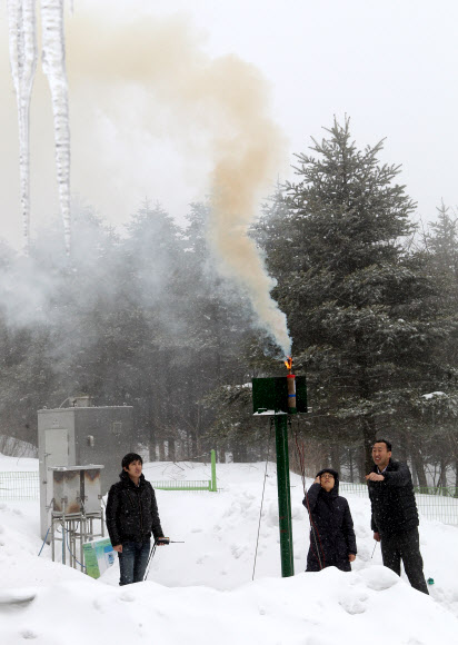 기상청 연구원들이 지난 9일 구름씨앗으로 쓰이는 요오드화은을 산의 경사면을 타고 부는 바람을 이용해 구름 속으로 올려 보내는 인공강설 실험 과정을 선보이고 있다.  연합뉴스