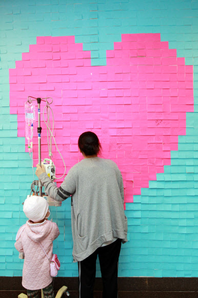 20일 오전 서울시 강남구 일원동 삼성서울병원에서 환자들이 빠른 쾌유를 기원하는 메시지를 벽면에 부착된 포스트잇에 적고 있다. 연합뉴스