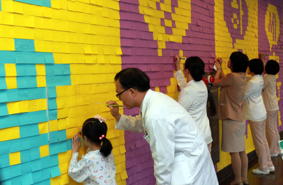 20일 오전 서울시 강남구 일원동 삼성서울병원에서 의사와 환자들이 빠른 쾌유를 기원하는 메시지를 벽면에 부착된 포스트잇에 적고 있다.  연합뉴스