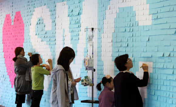 20일 오전 서울시 강남구 일원동 삼성서울병원에서 의사와 환자들이 빠른 쾌유를 기원하는 메시지를 벽면에 부착된 포스트잇에 적고 있다.