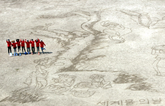 대한적십자사와 서울시립대학교 미술대학생 7명들이 ‘세계 물의 날’을 맞아 21일 서울 송파구 탄천 축구장에서 물로 신윤복의 ‘단오풍정’을 그려내고 있다.  연합뉴스
