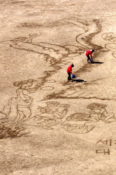 대한적십자사와 서울시립대학교 미술대학생 7명들이 ‘세계 물의 날’을 맞아 21일 서울 송파구 탄천 축구장에서 물로 신윤복의 ‘단오풍정’을 그려내고 있다.  연합뉴스