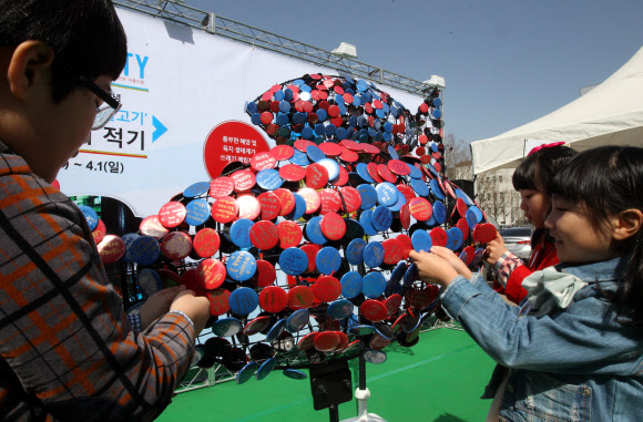 서울시청앞 광장에서 환경보호의 일환으로 개최한 “우정의 물고기” 희망 이벤트. 어린이들이 희망의 메시지를 적은 뱃지를 물고기 조형물에 부착하고 있다. 연합뉴스