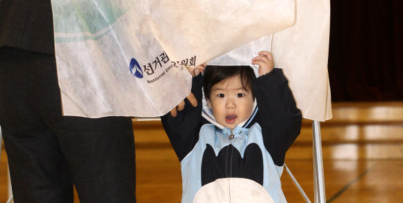 11일 오전 서울 종로구 국립서울농학교 청운.효자동 제1투표소에서 한 아이가 엄마가 기표하는 동안 신기한 듯 주변을 보고 있다.