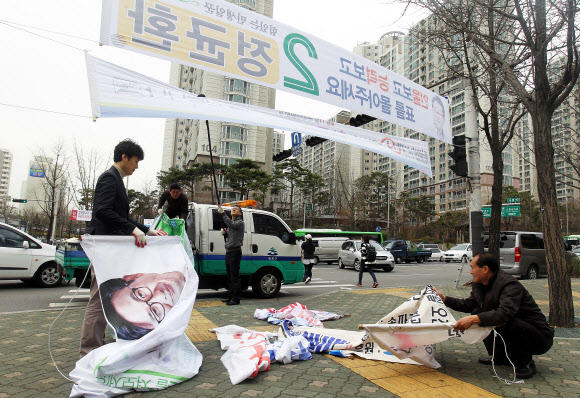 송파구청 주택관리과 직원들이 12일 오전 서울 송파구 오금동 개롱역 사거리에 설치된 제19대 국회의원선거 현수막들을 수거 하고 있다. 수거된 현수막은 농민들에게 제공되어 다양하게 활용 된다. 연합뉴스