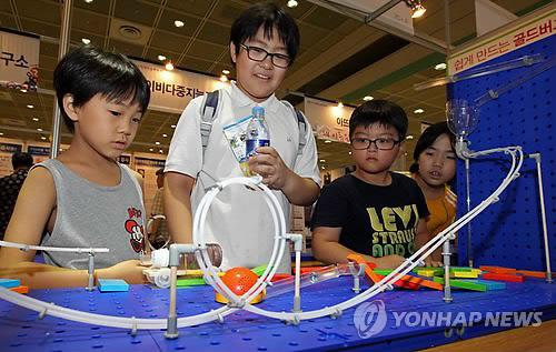 지난 해 8월 서울 삼성동 코엑스에서 열린 영재학습박람회에 참가한 어린이들이 즐거운 표정으로 도미노를 이용한 장치를 관찰하고 있다.  연합뉴스 