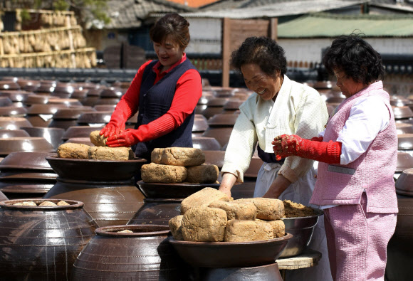 전통 된장 마을로 유명한 전남 강진군 군동면 신기마을을 찾는 관광객과 주민들이 18일 직접 된장을 만드는 체험을 하며 즐거워하고 있다.  연합뉴스