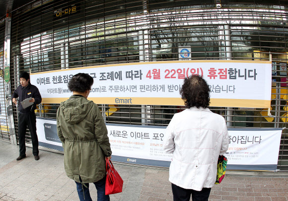 대형마트와 기업형 슈퍼마켓(SSM)의 의무휴업이 첫 시행된 22일 서울 강동구 이마트를 찾은 고객들이 휴점 안내문을 보고 있다. 연합뉴스