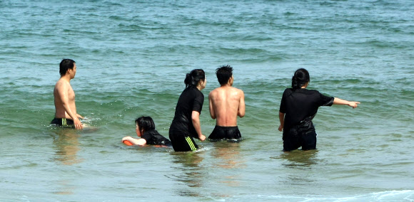 강릉지방의 낮 기온이 27도까지 올라가는 등 동해안 지방의 낮기온이 20도를 훌쩍 넘어서 더위를 느끼게 한 24일 오후 속초해변을 찾은 젊은이들이 바다에 뛰어들어 열기를 식히고 있다. 연합뉴스