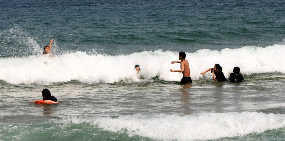 강릉지방의 낮 기온이 27도까지 올라가는 등 동해안 지방의 낮기온이 20도를 훌쩍 넘어서 더위를 느끼게 한 24일 오후 속초해변을 찾은 젊은이들이 바다에 뛰어들어 열기를 식히고 있다. 연합뉴스