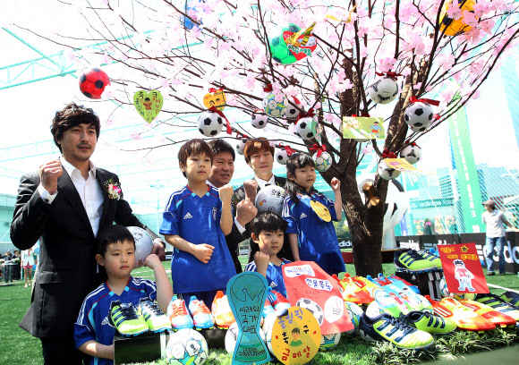 26일 오전 서울 용산 아이파크몰 옥상공원 풋살 경기장에서 열린 ‘아디다스 올인파크’ 오픈 행사에서 안정환 K리그 홍보대사(왼쪽부터), 정몽규 현대산업개발그룹 회장, 송종국 전 국가대표가 어린이들과 ‘축구사랑 소망나무’ 앞에서 기념촬영을 하고 있다.