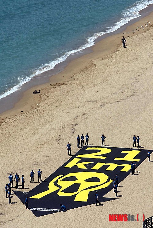 27일 오전 부산 해운대해수욕장 백사장에서 국제환경단체인 ‘그린피스’의 활동가들이 원전의 위험성을 알리는 대형 배너(가로 10m, 세로 30m)를 펼쳐보이고 있다.