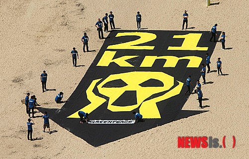 27일 오전 부산 해운대해수욕장 백사장에서 국제환경단체인 ‘그린피스’의 활동가들이 원전의 위험성을 알리는 대형 배너(가로 10m, 세로 30m)를 펼쳐보이고 있다.