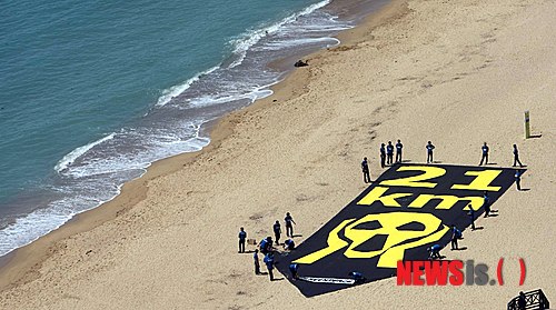 27일 오전 부산 해운대해수욕장 백사장에서 국제환경단체인 ‘그린피스’의 활동가들이 원전의 위험성을 알리는 대형 배너(가로 10m, 세로 30m)를 펼쳐보이고 있다.