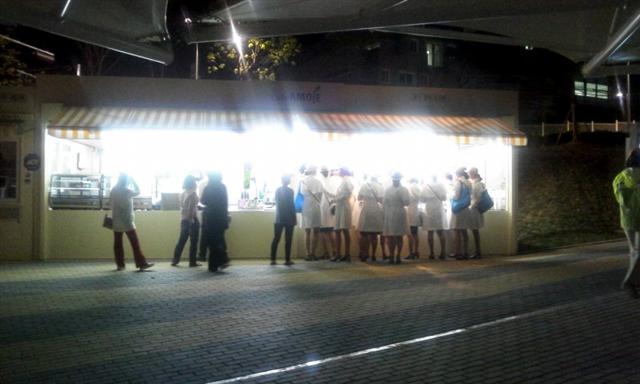 폐장 직후 흰색 코트 차림의 여성 도우미들이 엑스포타운 앞 임시 카페에 모여 핫도그 등 야식을 주문하고 있다.