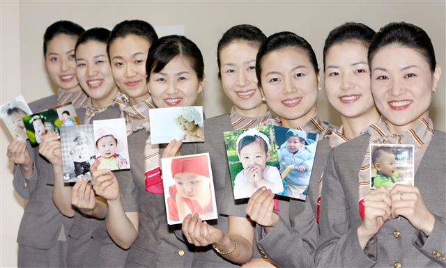 최근 출산휴가를 끝내고 복직한 아시아나항공 여직원들이 자녀 사진을 들고 포즈를 취하고 있다.  아시아나항공 제공