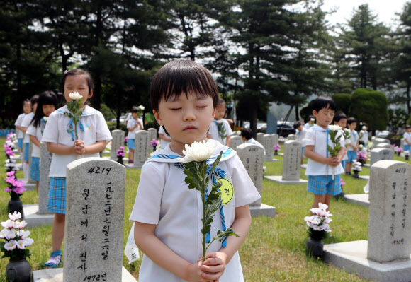 호국보훈의 달을 맞은 6월의 첫 날인 1일 서울 동작구 국립현충원을 찾은 관내 유치원생들이 묘역 앞에서 두 손을 모은채 묵념을 하고 있다.  연합뉴스
