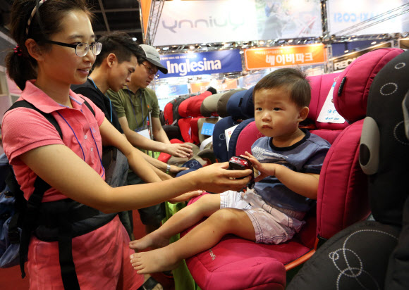 14일 오후 서울 양재동 aT센터에서 열린 ‘2012 베이비 키즈 페어’에서 한 관람객이 육아용 자동차 시트에 아이를 앉혀보고 있다. 연합뉴스