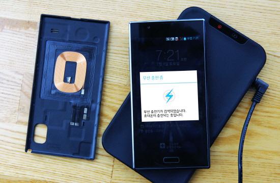 LG전자의 스마트폰 ‘옵티머스LTE2’(오른쪽)가 무선충전 패드 위에서 충전되고 있다. 왼쪽은 자기유도 방식의 무선충전 코일이 탑재된 스마트폰 배터리 커버. LG전자 제공