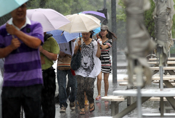 전국적으로 장맛비가 내린 30일 오전 서울 청계광장을 지나는 외국인 관광객들이 비바람에 우산을 움켜쥐고 걷고 있다. 연합뉴스