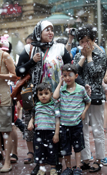 5일 서울 잠실 롯데월드에서 외국인 관람객들이 인공눈이 내리는 가운데 삼바댄서들의 공연을 관람하고 있다. 연합뉴스