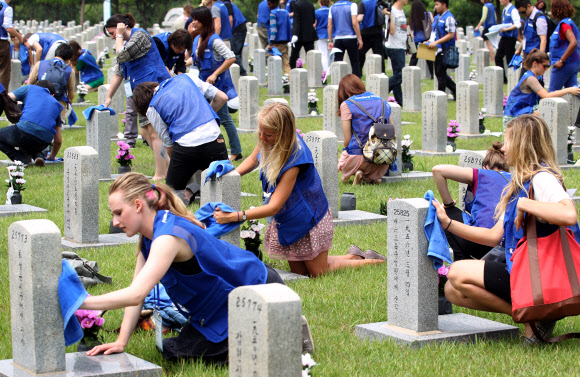 9일 오전 서울 동작동 국립서울현충원에서 UN 참전국 청소년 평화캠프 참가자들이 참전용사 묘역에서 묘비를 닦고 있다. 연합뉴스